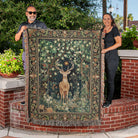 Two people holding a large tapestry with a deer design outdoors.