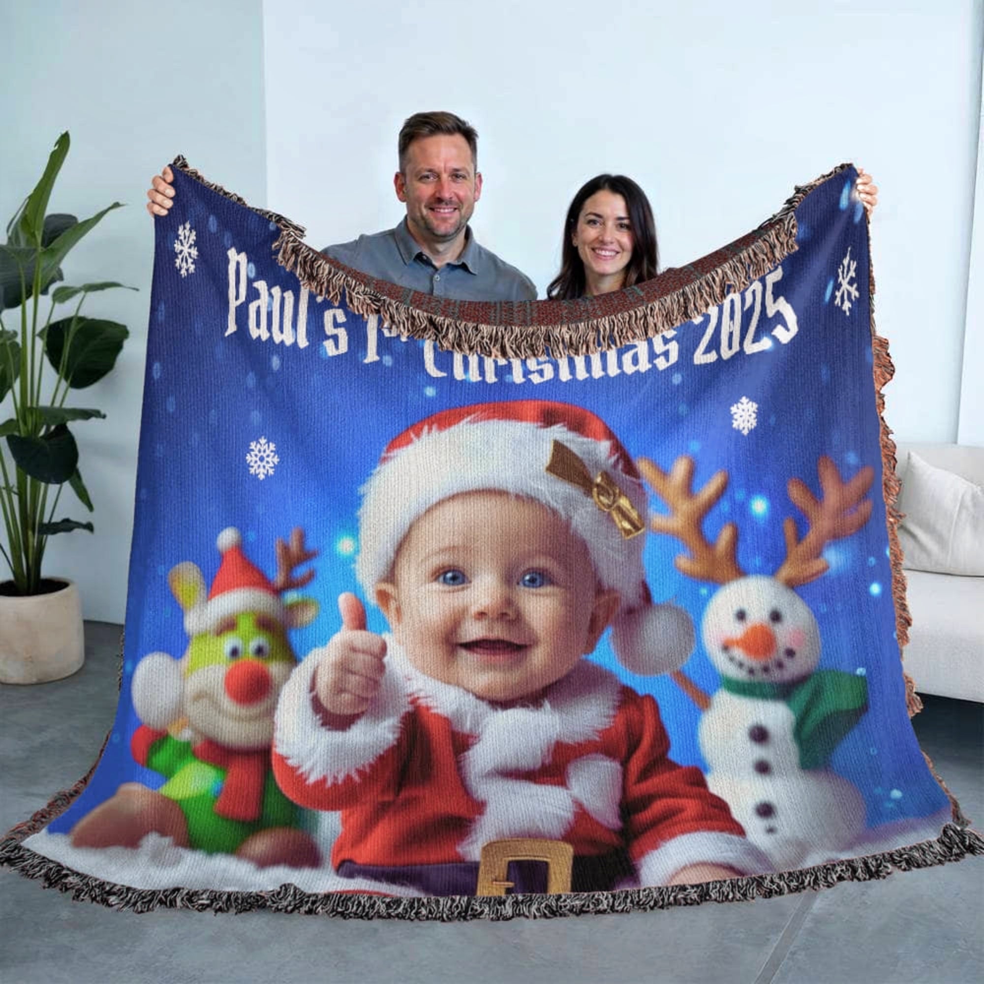 Blanket with a child in a Santa outfit and Christmas-themed design, held by two people.